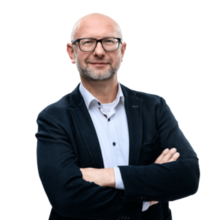 Mann mit Brille im Sakko steht mit verschränkten Armen