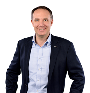 Person im Business-Outfit lächelt in einer Porträtaufnahme.