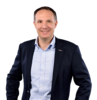 Person im Business-Outfit lächelt in einer Porträtaufnahme.